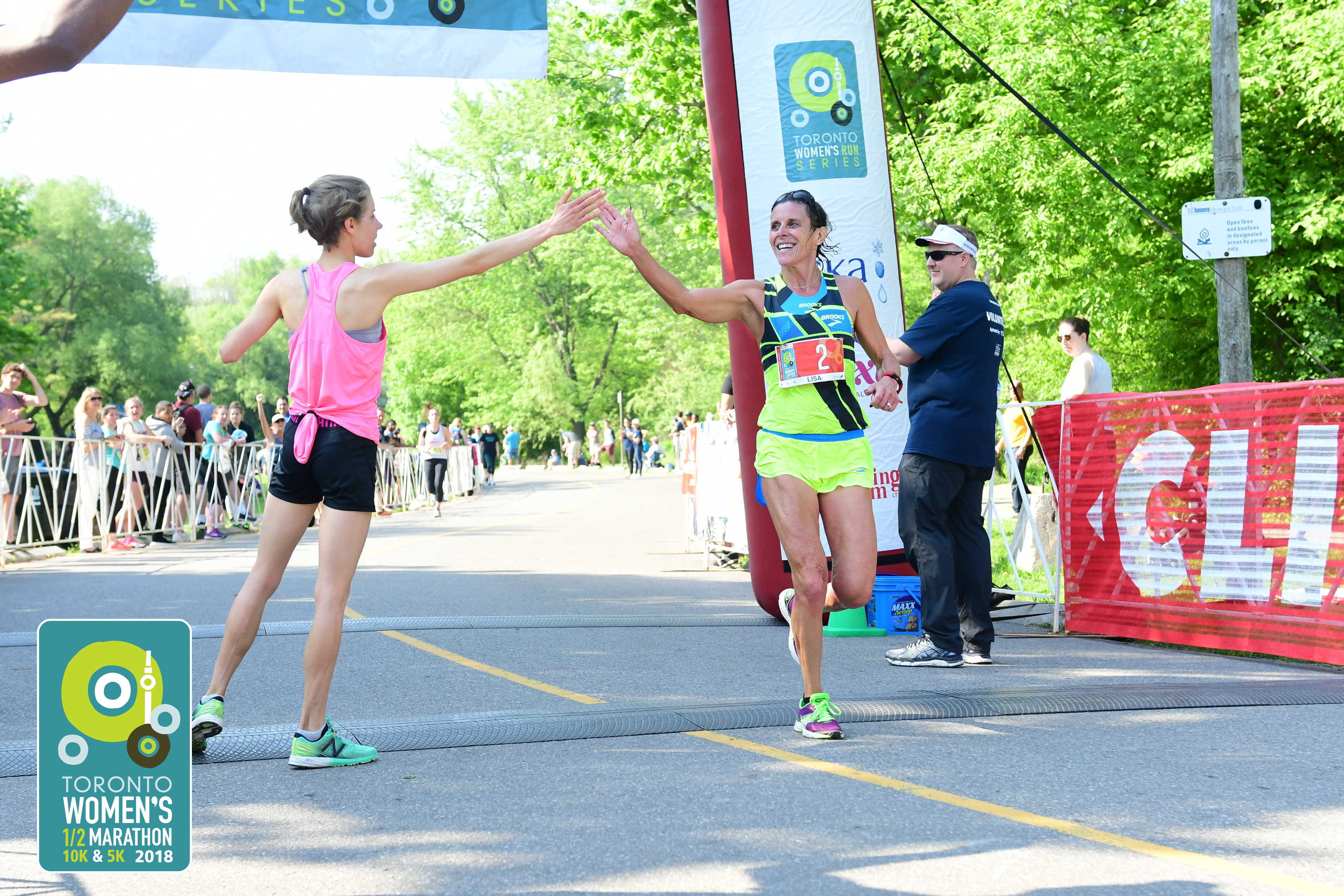 Lisa Bentley crossing finish line in marathon and high fiving volunteer