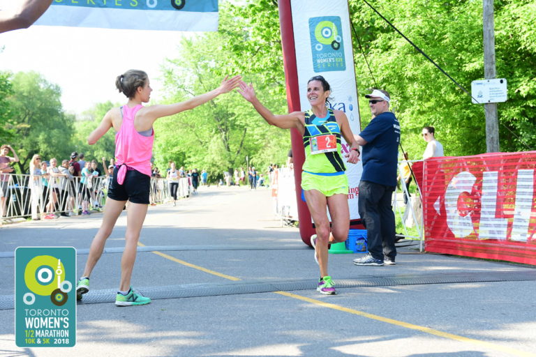 Lisa Bentley crossing finish line in marathon and high fiving volunteer